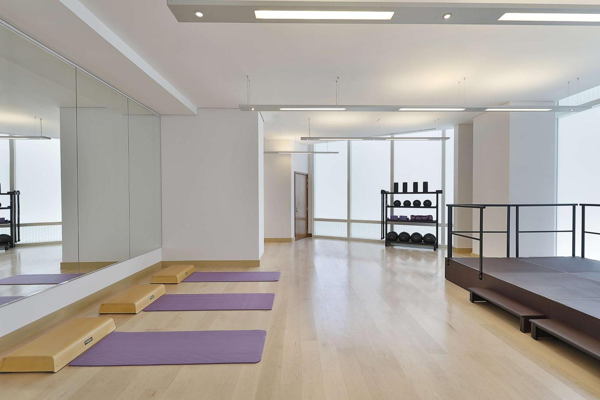 Hilton Riyadh Hotel & Residences Eksteriør billede The photo depicts a spacious exercise or workout studio. It features wooden flooring and a large mirror on one wall. There are three purple yoga mats neatly placed on the floor, and a small set of wooden steps beside them. In the background, there is