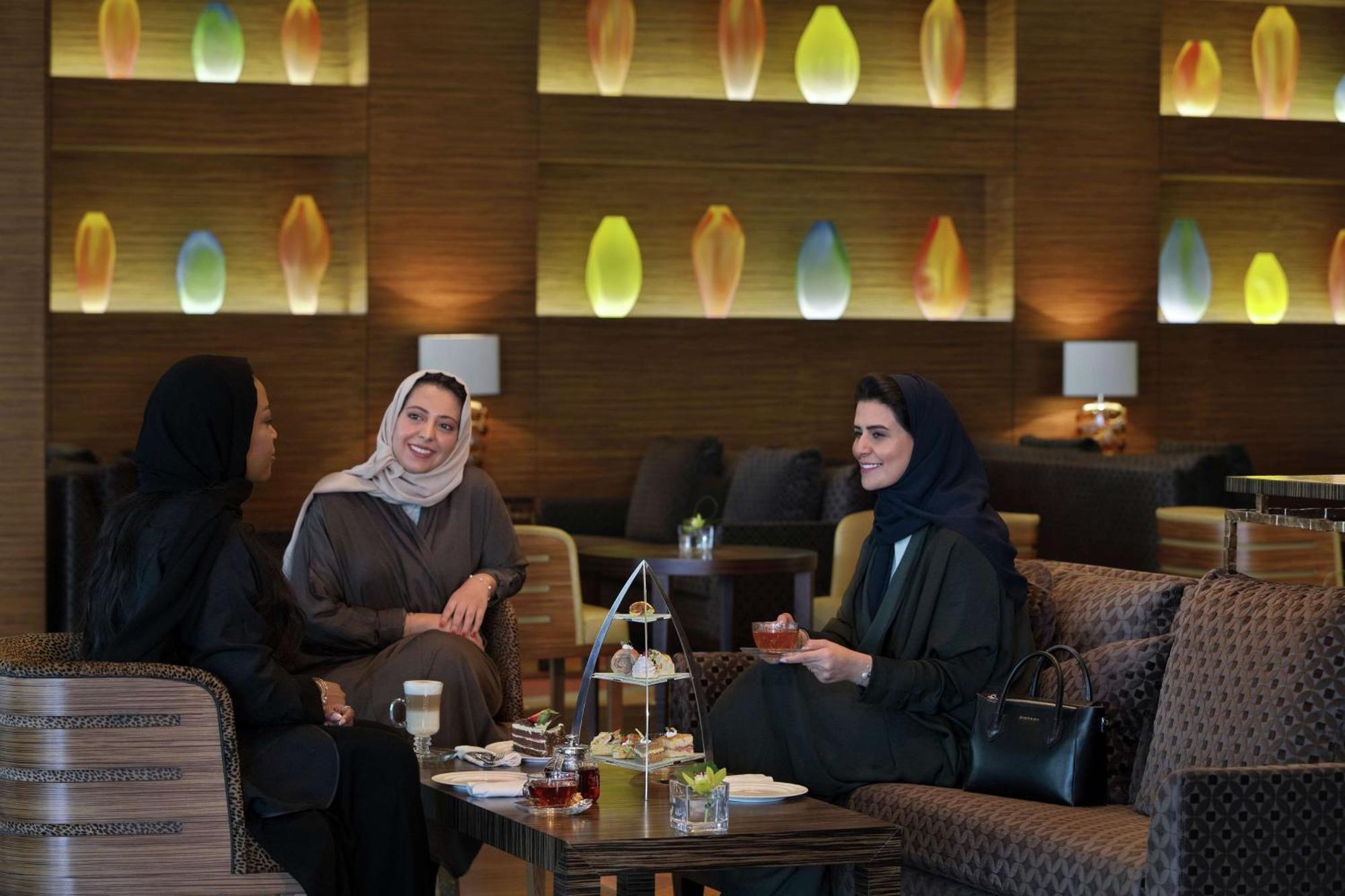Hilton Riyadh Hotel & Residences Eksteriør billede The photo shows three women sitting together in a cozy, well-decorated lounge. They appear to be enjoying each other's company, engaged in conversation and possibly sharing tea or refreshments. The setting features soft, modern lighting with decorati
