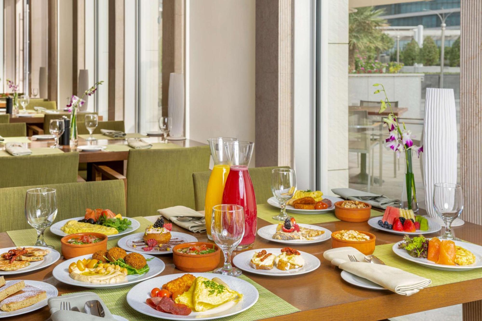 Hilton Riyadh Hotel & Residences Eksteriør billede The photo showcases a beautifully arranged dining table filled with a variety of dishes. There are multiple plates featuring an assortment of foods, including salads, appetizers, and main courses, presented in a vibrant and appetizing manner. Additio